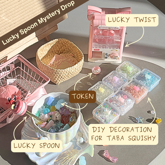 Collection of items including a Lucky Claw machine,TOKEN, and DIY decoration for BellaMoon Taba Squishy on a table.